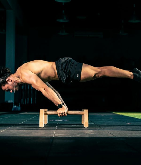 Man performing a controlled strength exercise in a minimalist dark environment.